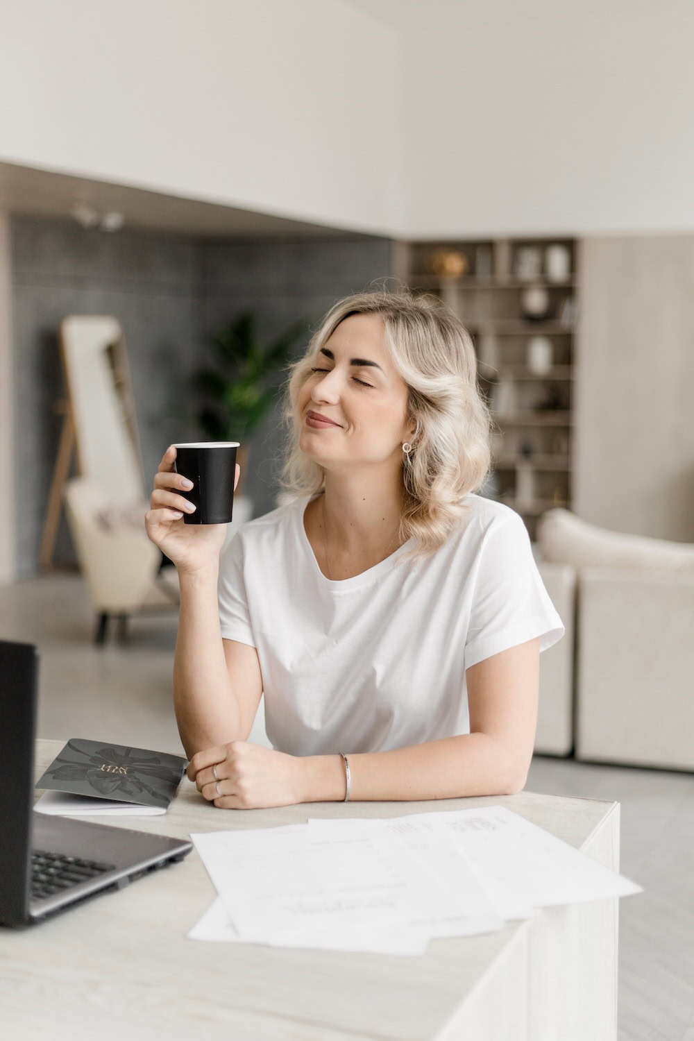 Hochzeitsplanerin sitzt entspannt am Tisch mit Kaffee und Unterlagen – Sinnbild für Ruhe und Klarheit im Arbeitsalltag der Hochzeitsplanung.
