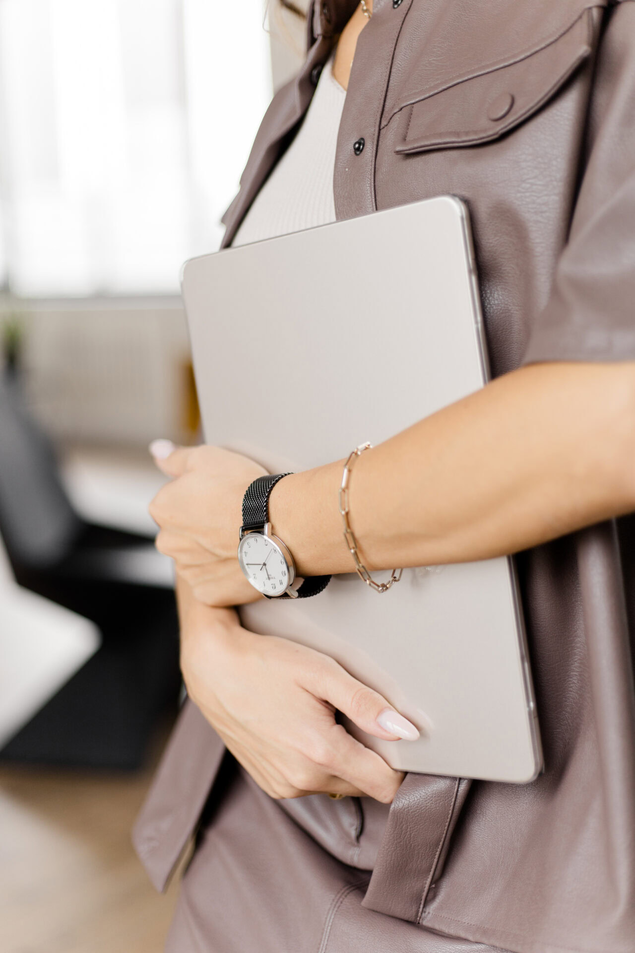Eine Hochzeitsplanerin hält einen Laptop unter dem Arm – Symbol für klare Organisation und Übersicht im Arbeitsalltag.