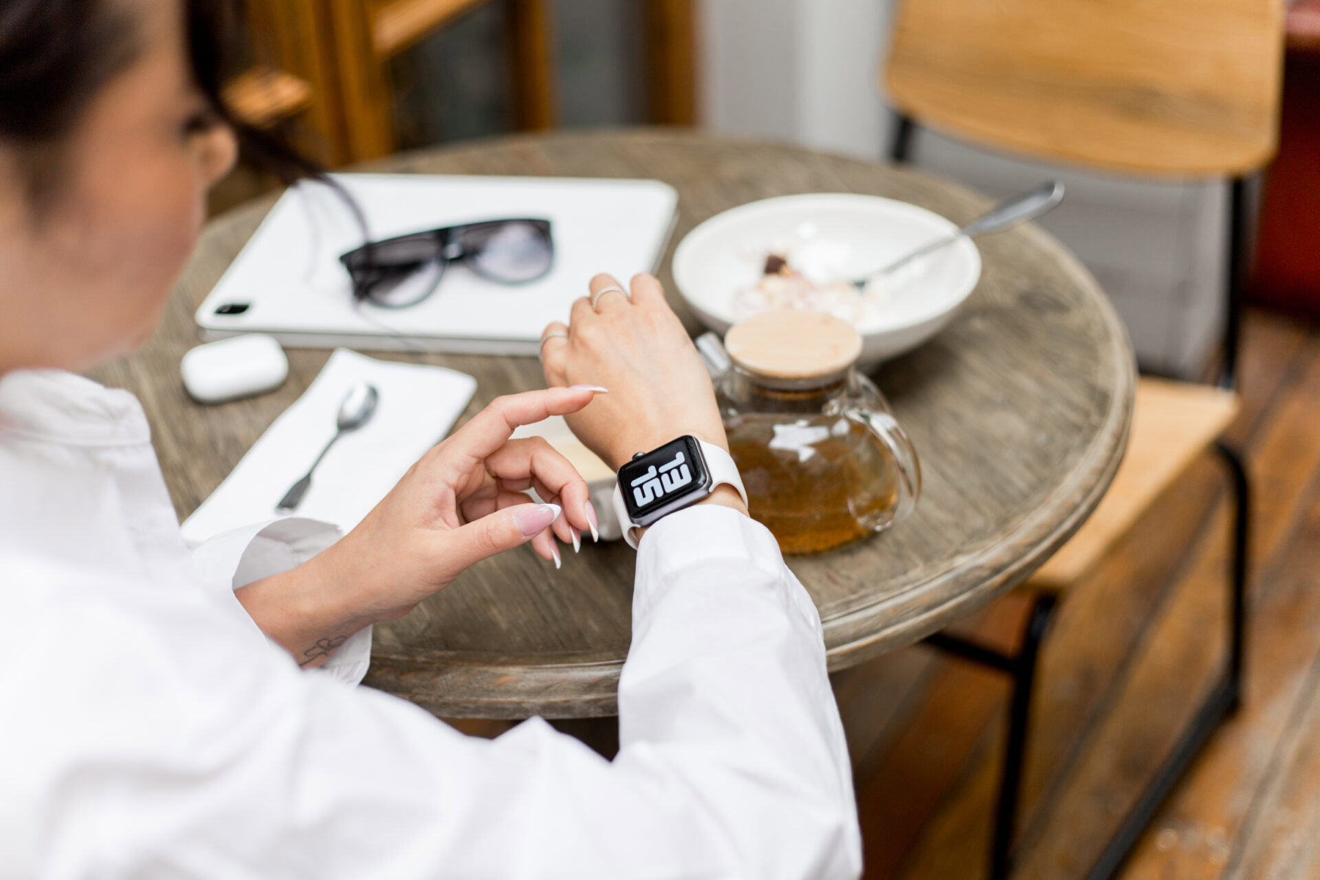 Hochzeitsplanerin prüft die Uhr während einer Pause im Café – Sinnbild für fehlenden mentalen Feierabend.