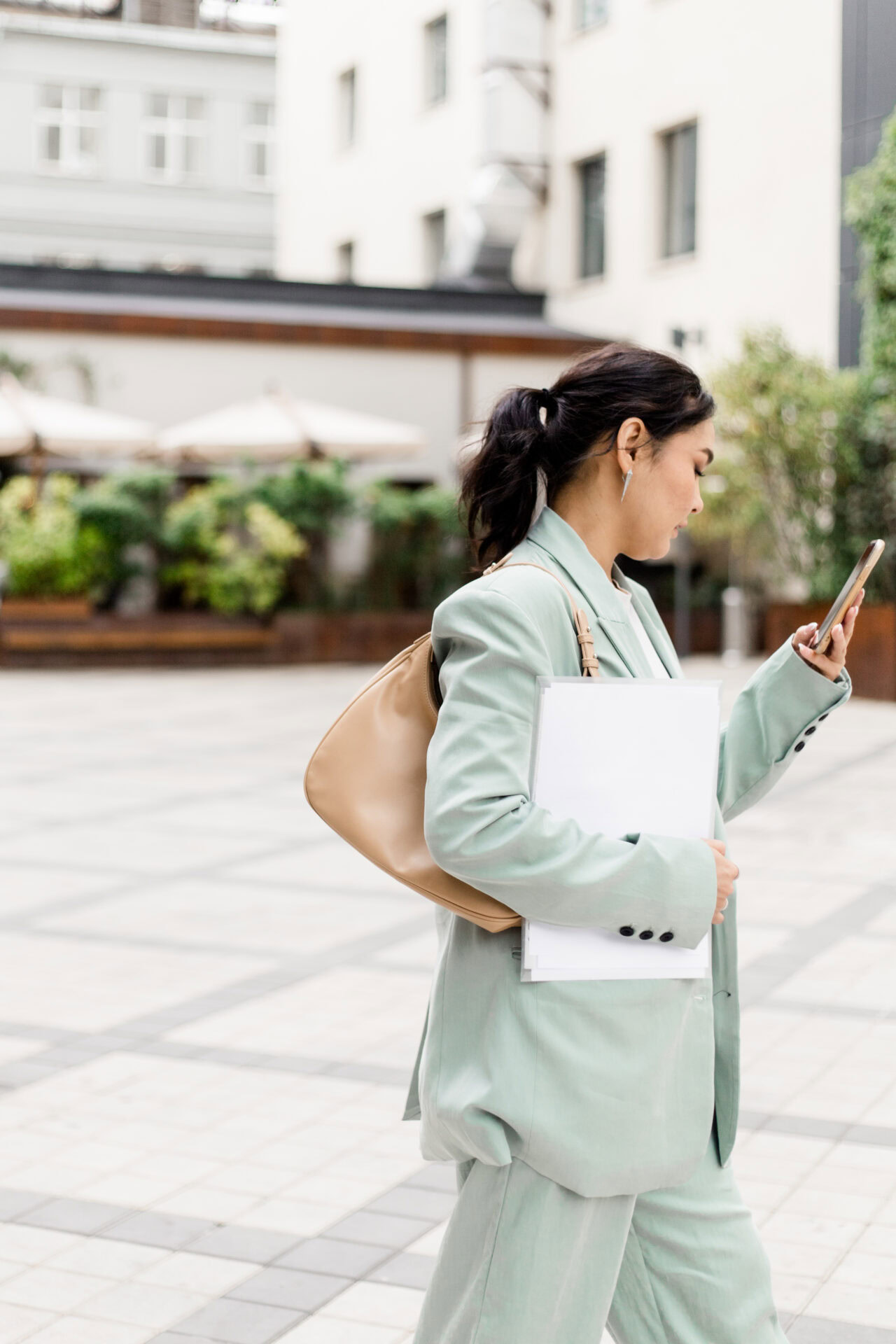 Hochzeitsplanerin unterwegs mit Unterlagen und Smartphone – Arbeit begleitet sie auch außerhalb des Büros.