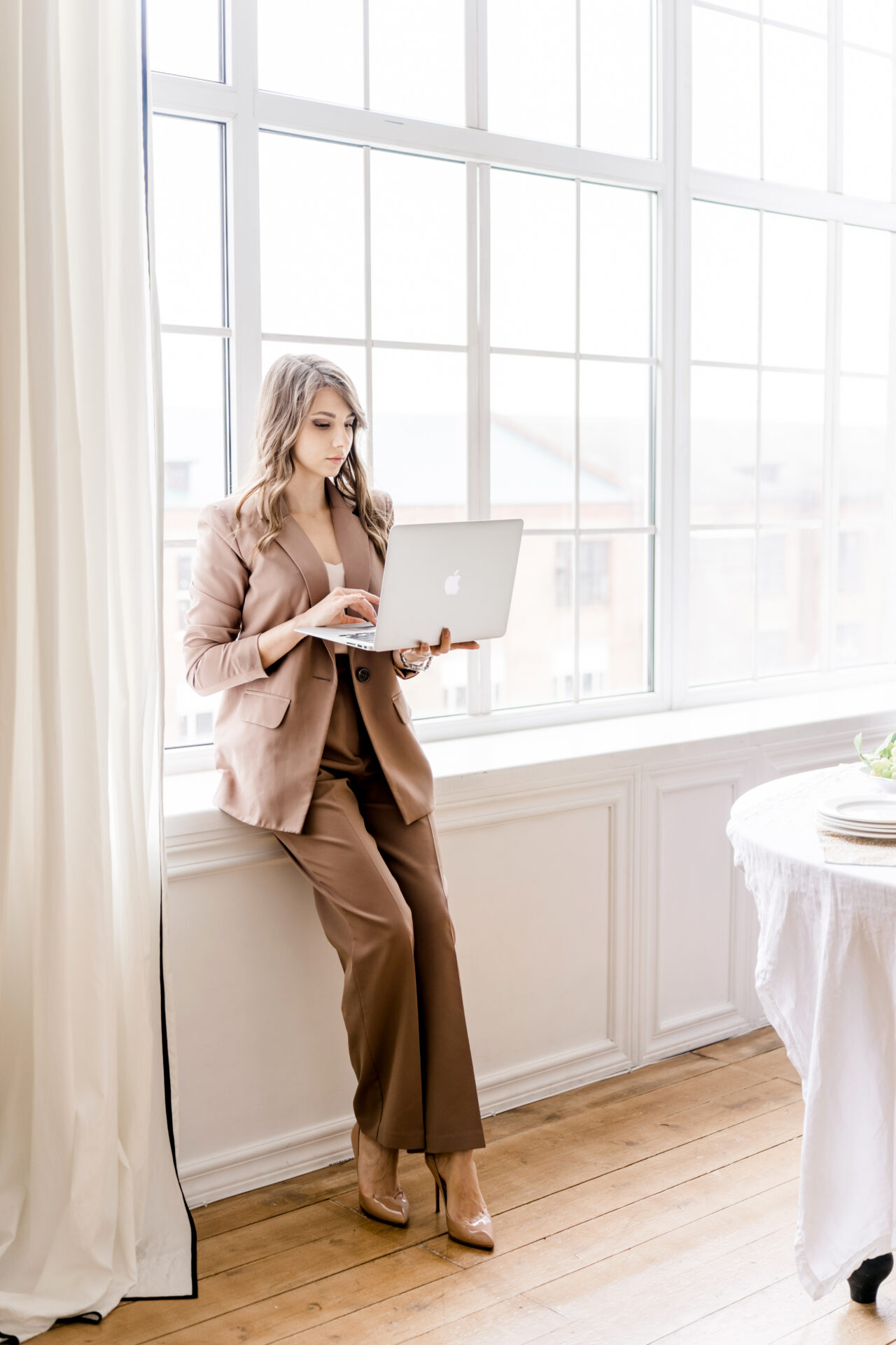 Hochzeitsplanerin steht ruhig mit Laptop am Fenster – Sinnbild für Klarheit, Übersicht und ein System, das Entscheidungen trägt.