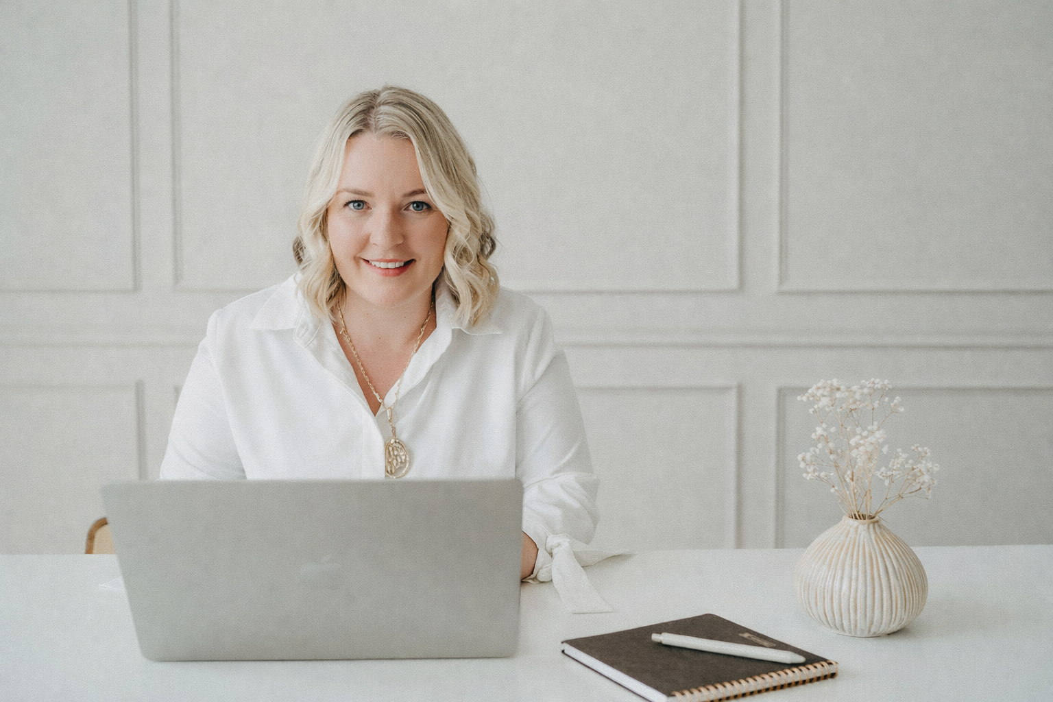 Porträt von Martina am Schreibtisch mit Laptop, Notizbuch und Vase