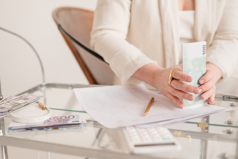 Hände halten Geldscheine über einem Tisch mit Unterlagen, Stift und Taschenrechner – Symbol für Notion Preise und Planwahl.