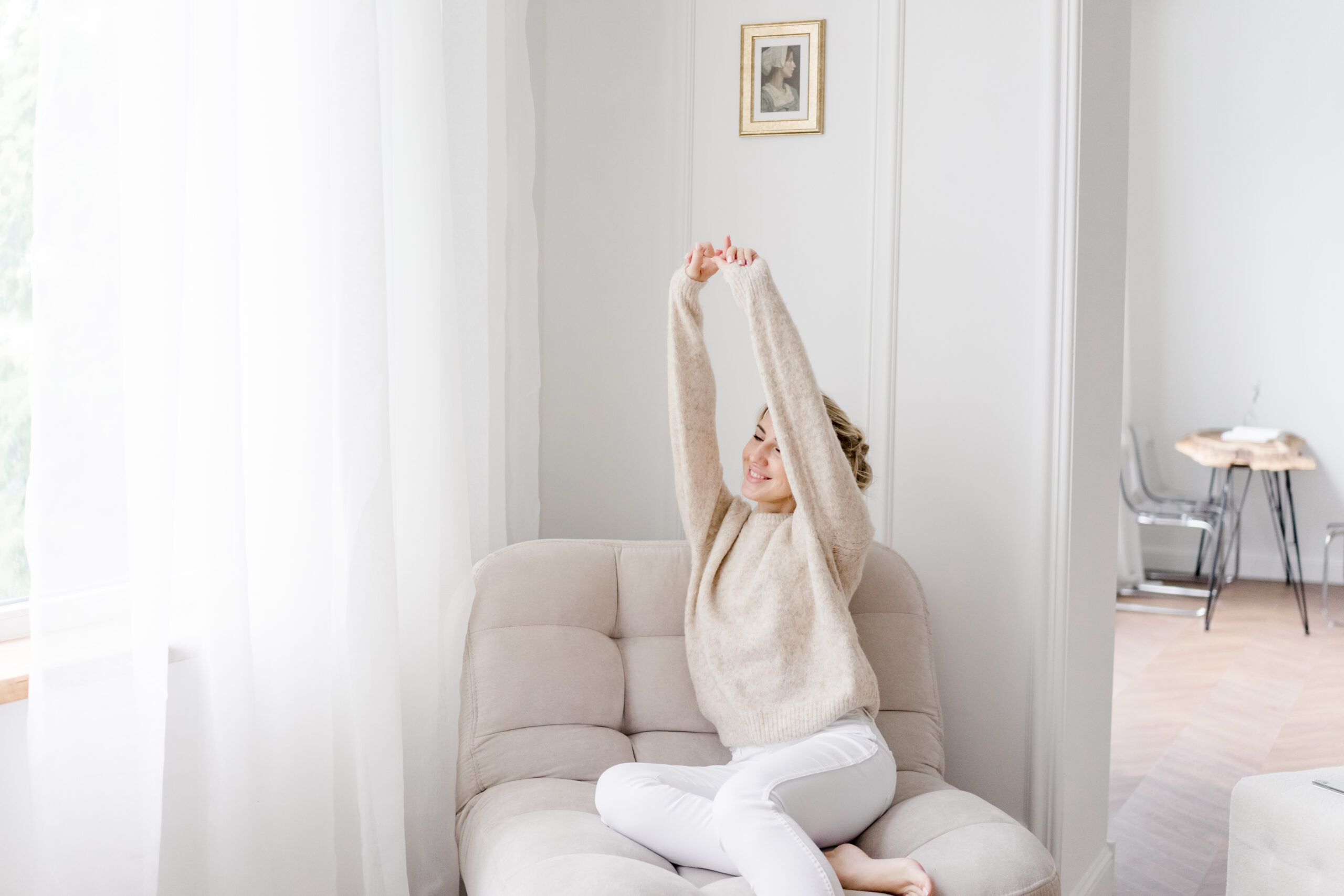 Frau sitzt entspannt in hellem Raum und streckt die Arme – Sinnbild für mentale Entlastung durch Klarheit und Überblick im Businessalltag von Hochzeitsplanerinnen.