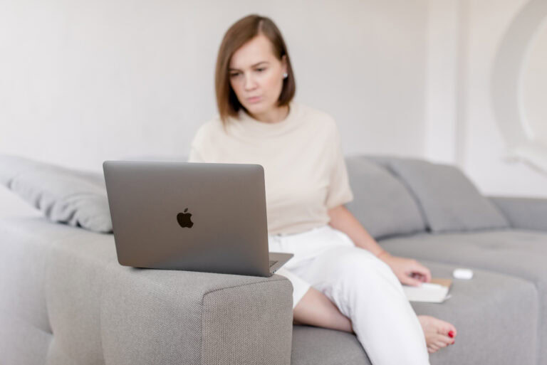 Hochzeitsplanerin sitzt mit Laptop auf dem Sofa und prüft ihre Arbeit – Sinnbild für Reflexion, Überblick und bewusste Entscheidungen im Hochzeitsbusiness.